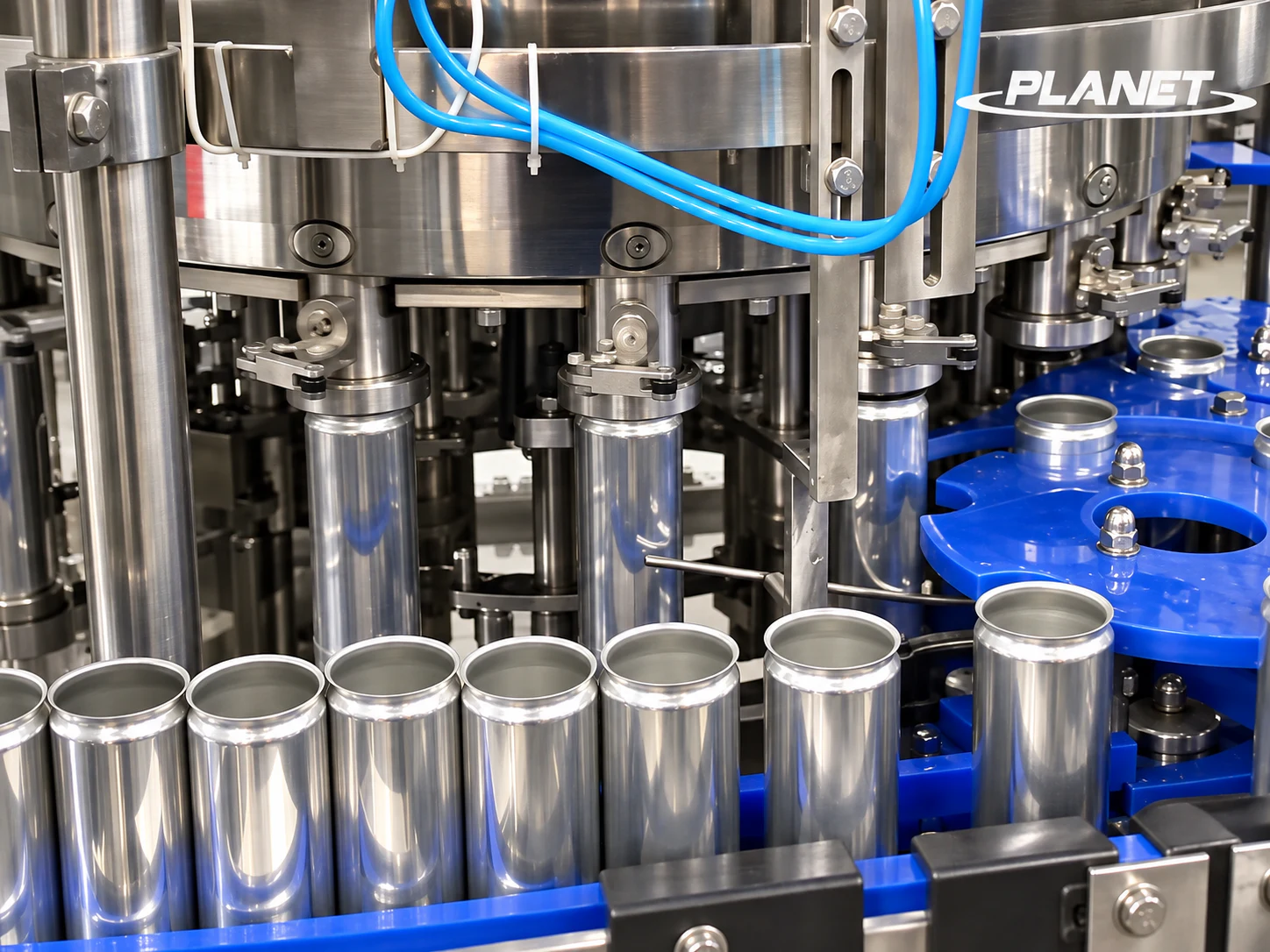 Close-up of unbranded beverage cans entering the rotary seaming heads of a carbonated drink canning machine