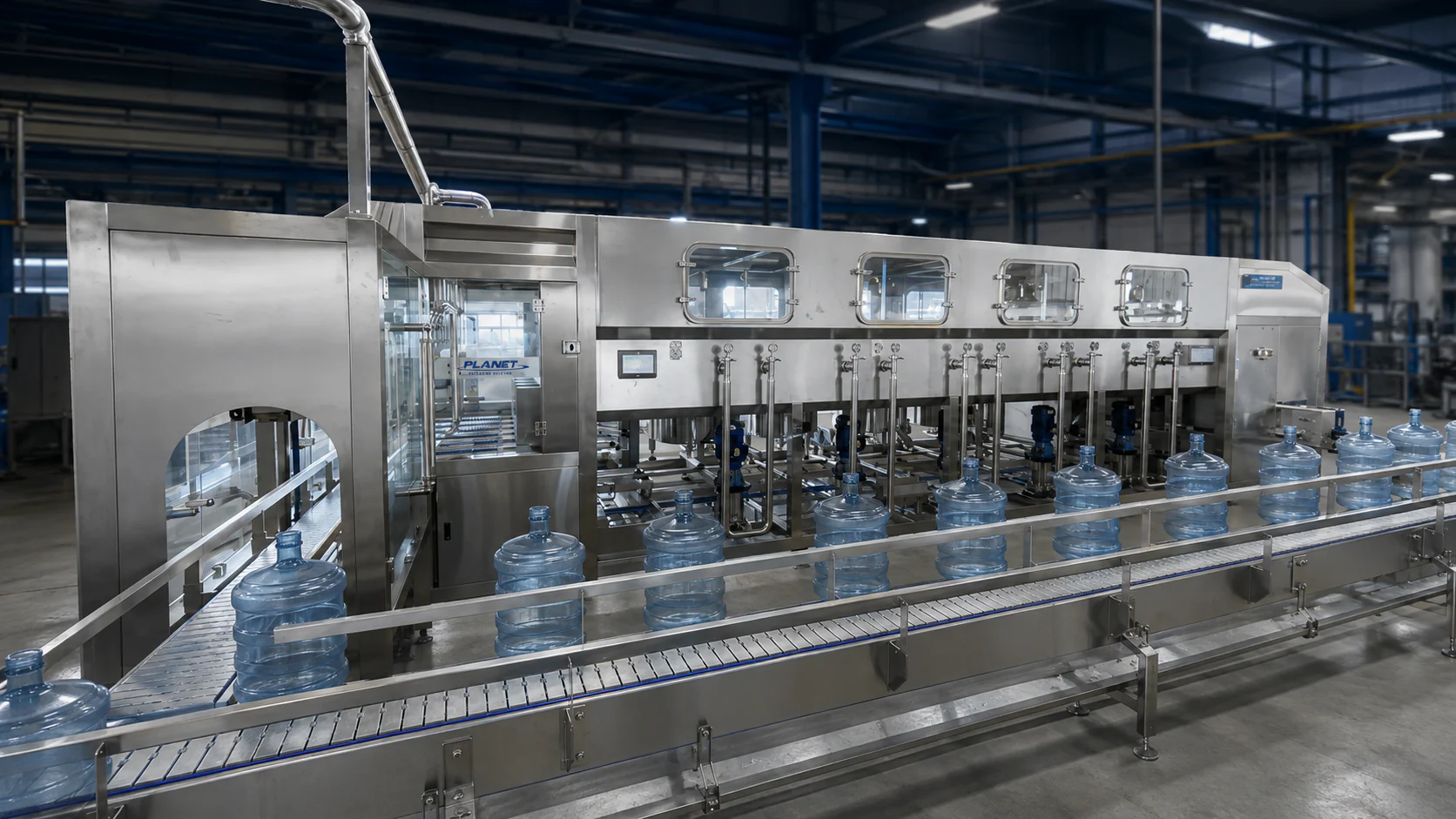 Five-gallon returnable bottles moving along the conveyor in front of the complete stainless-steel processing line