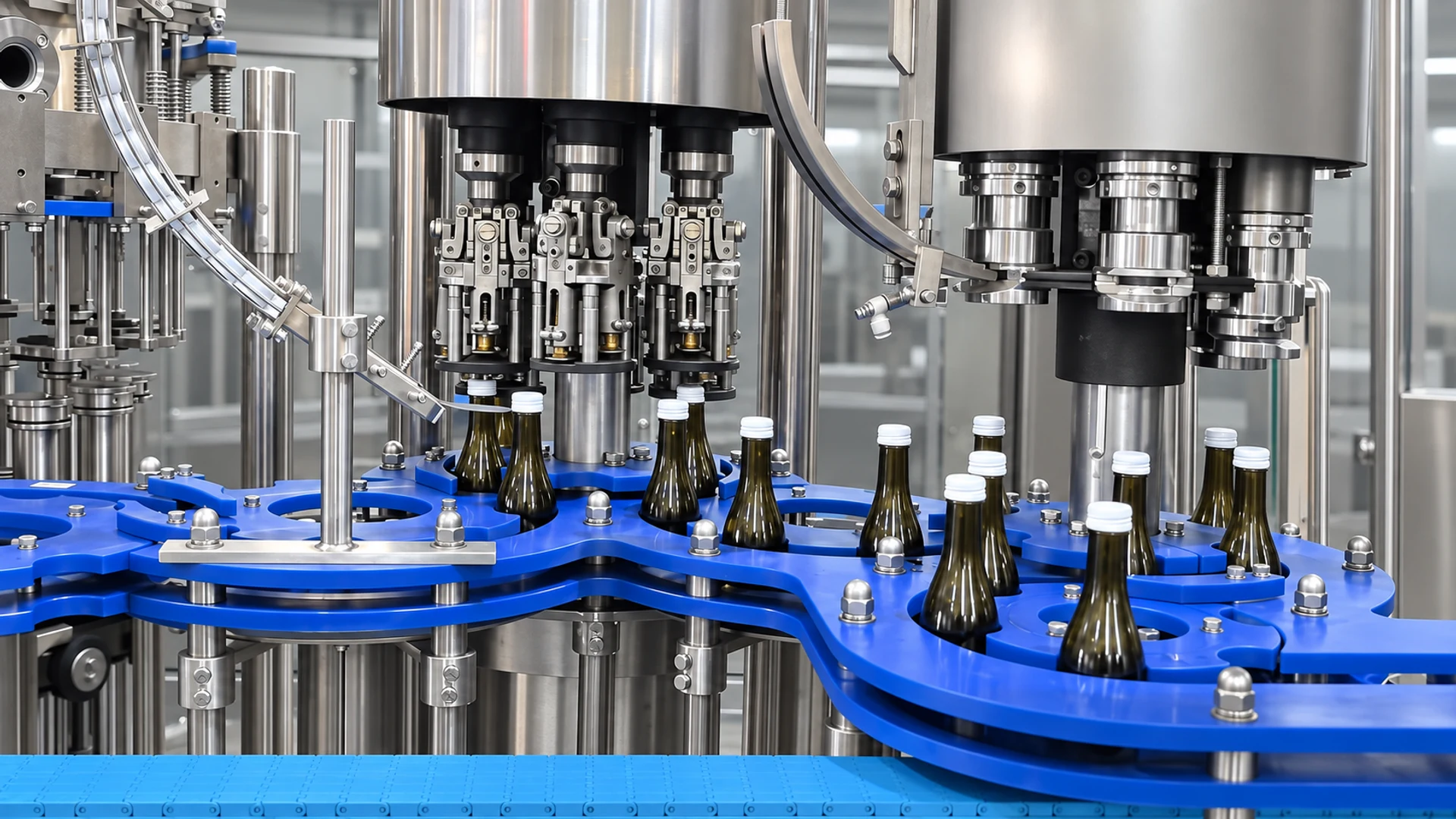 Dark glass beverage bottles moving through the filling and closing stations of a carbonated soft drink line