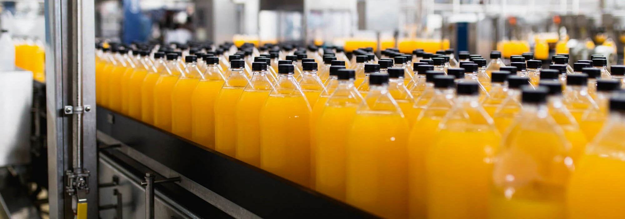Orange juice bottles moving along a conveyor inside an automated beverage filling plant
