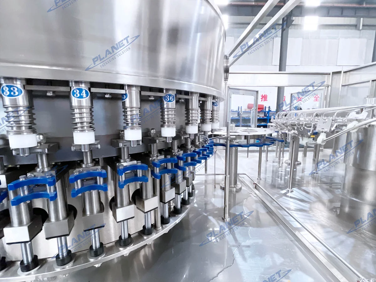 Rotary water filler valves and blue bottle-neck holders photographed inside the filling machine