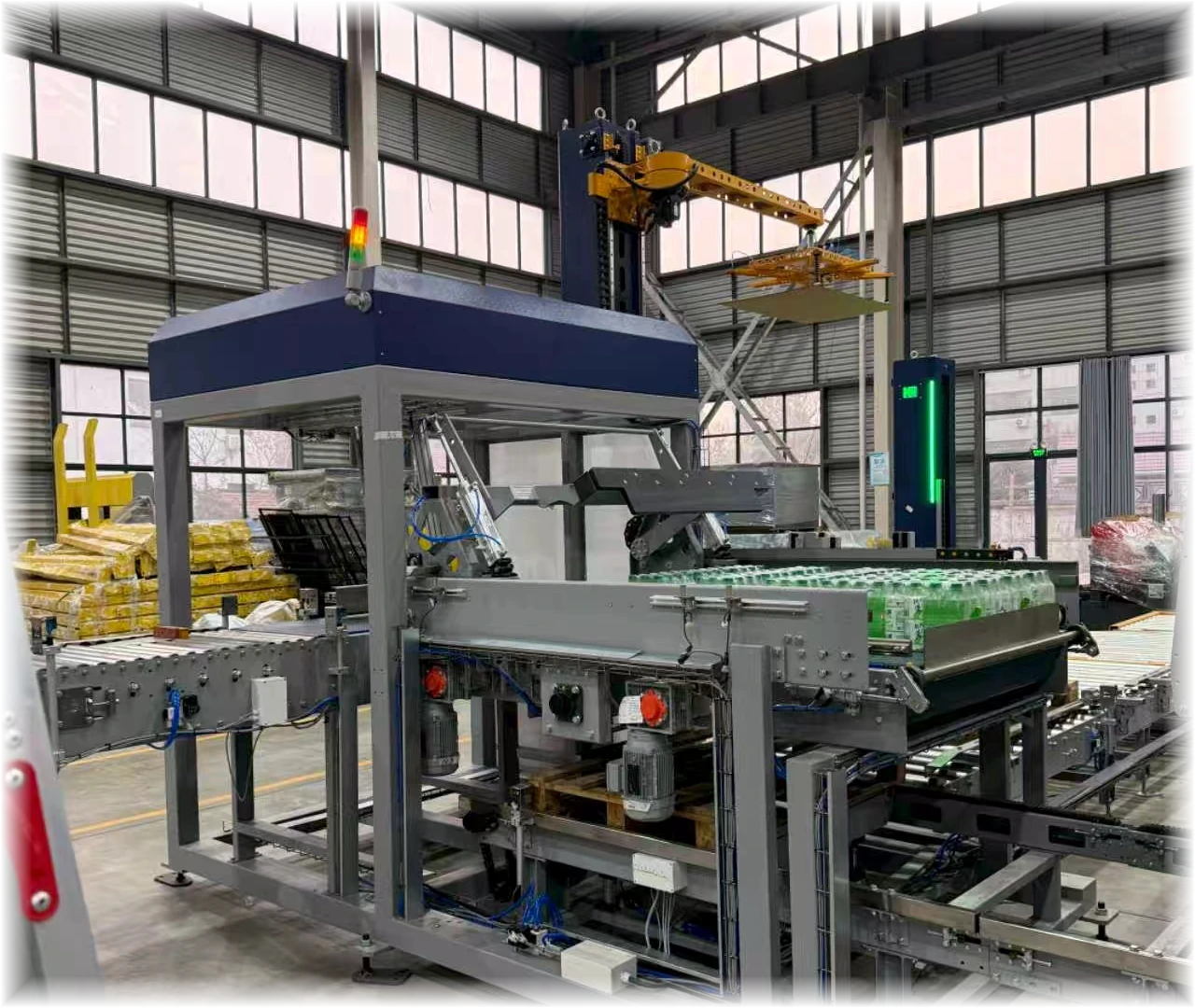 Automatic palletizer arranging finished bottled beverage packs inside a factory